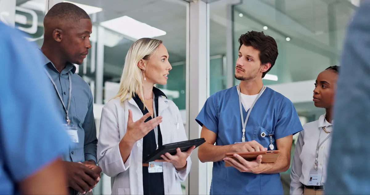 Three clinicians in discussion in a hospital corridor