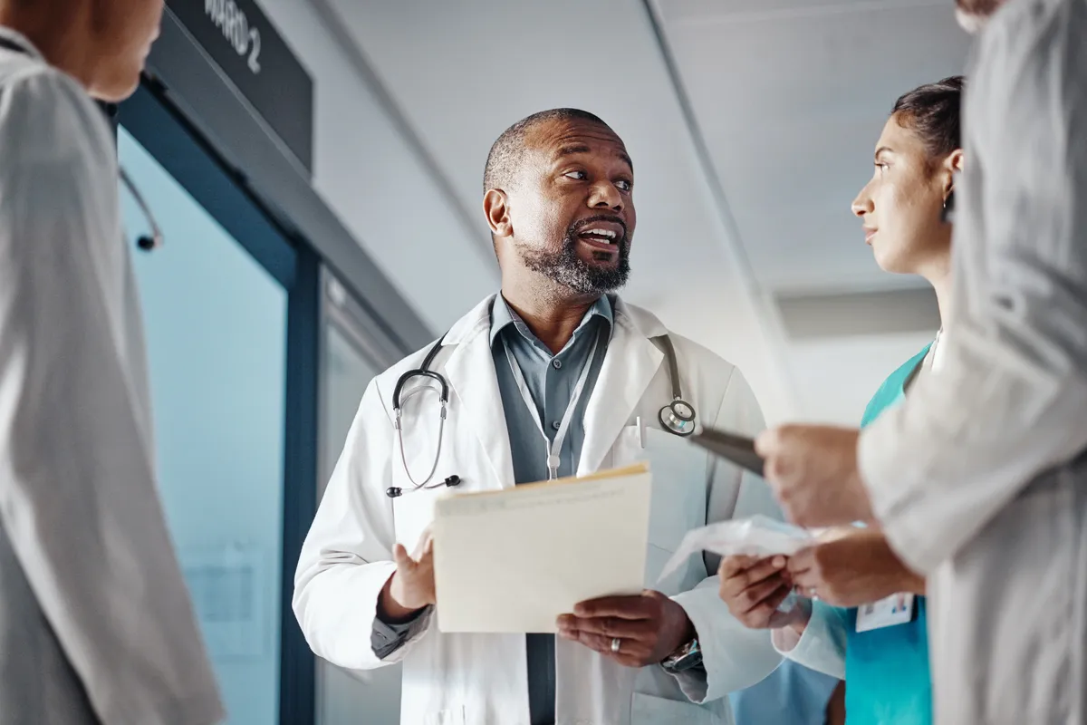 Doctor reviewing a patient folder with a nurse in a hospital corridor — Featured Offering: Medical Stop Loss