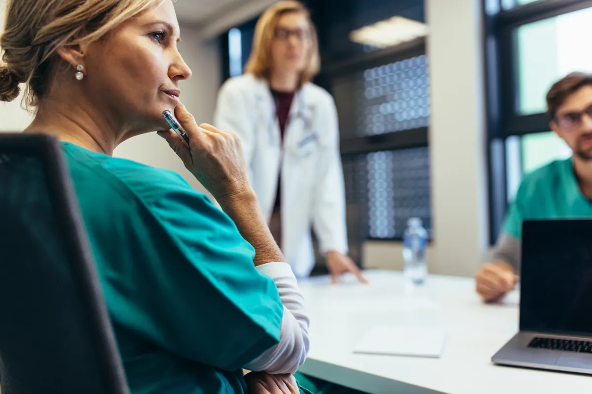 Nurse consulting with colleagues in a hospital hallway